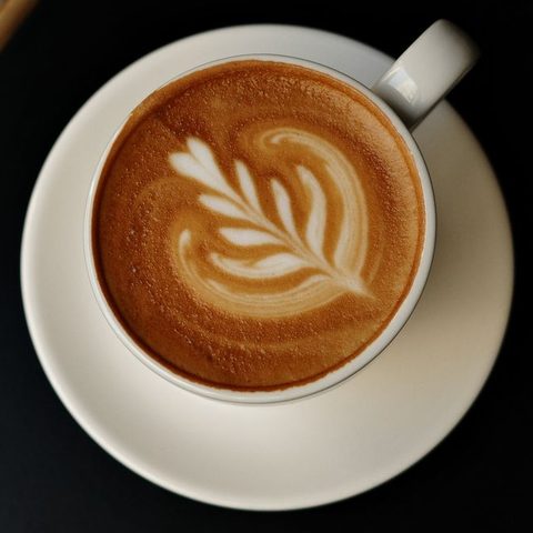 Latte art in a white cup on a dark table