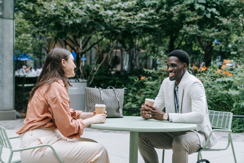 Two people talking over coffee at an outdoor café table