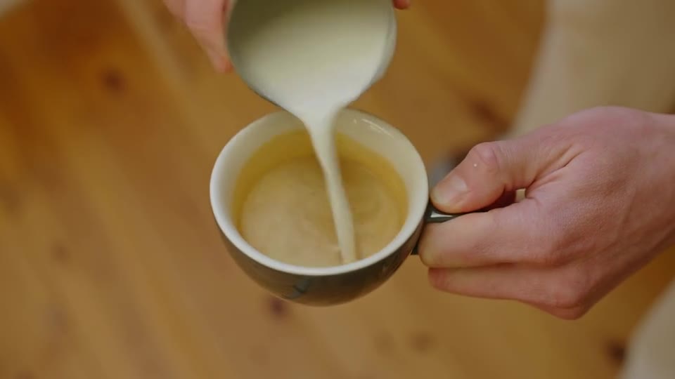 Milk being poured into an espresso, forming latte art